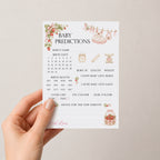 Hand holding Berry Sweet Baby A6 strawberry baby shower prediction keepsake card against a soft neutral background.