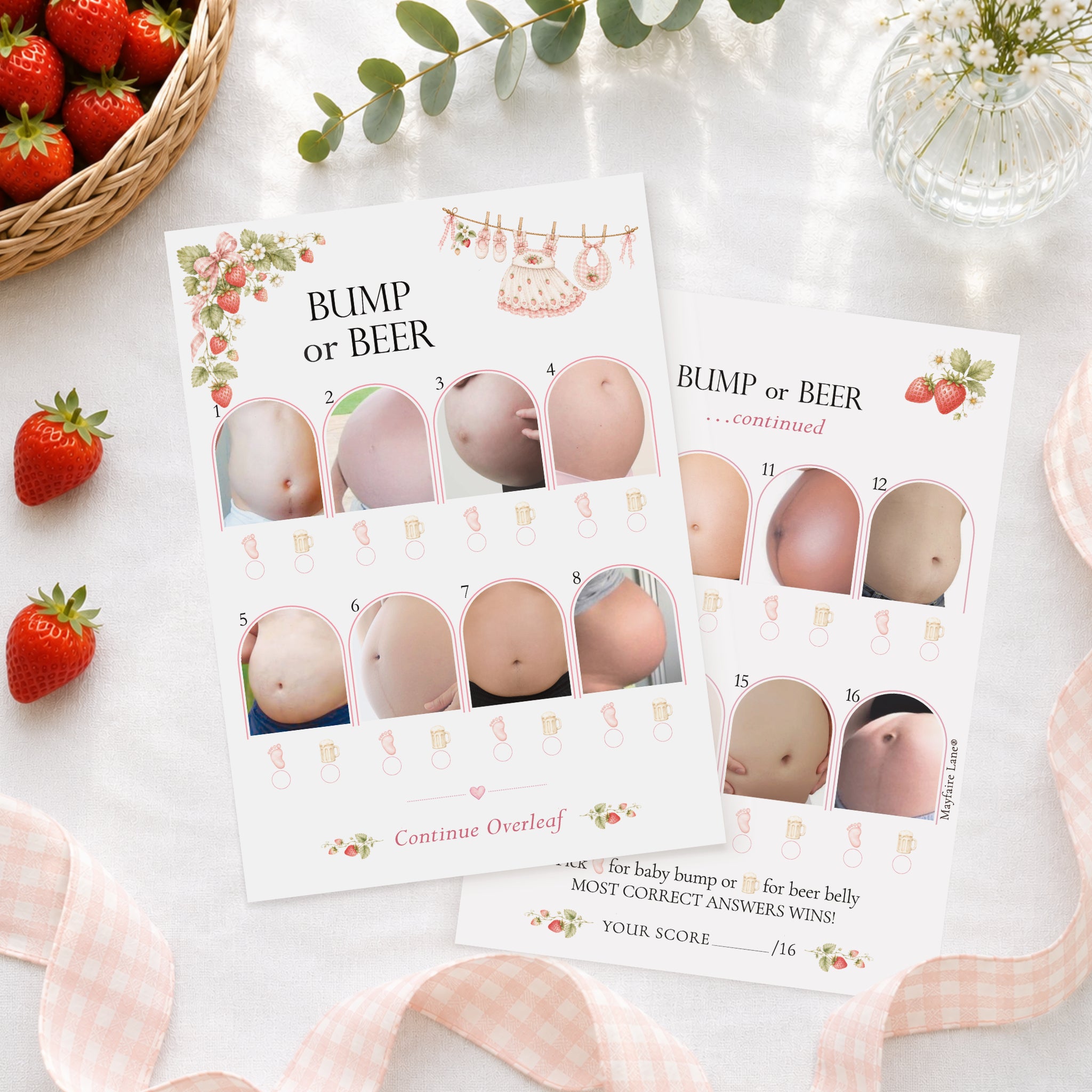 Berry Sweet Baby Bump or Beer double-sided A6 baby shower game cards styled with strawberries and elegant party décor arranged on a white surface with strawberries, a woven basket, greenery, and pink gingham ribbon around them. The cards show numbered belly photos and decorative floral accents.