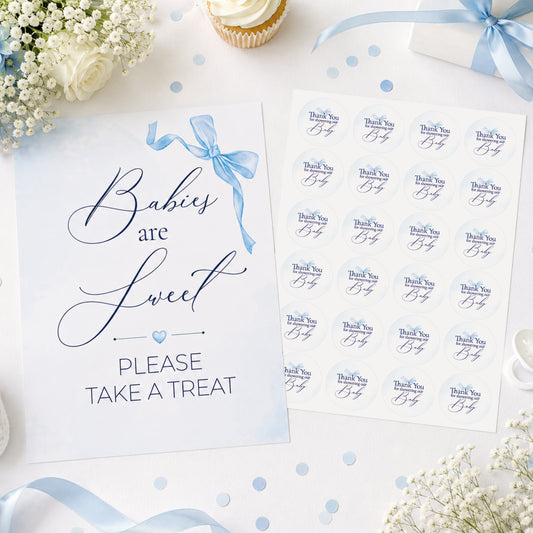 Blue bow baby shower sign and matching 37mm favour stickers styled on a baby shower table with flowers, ribbons and party treats