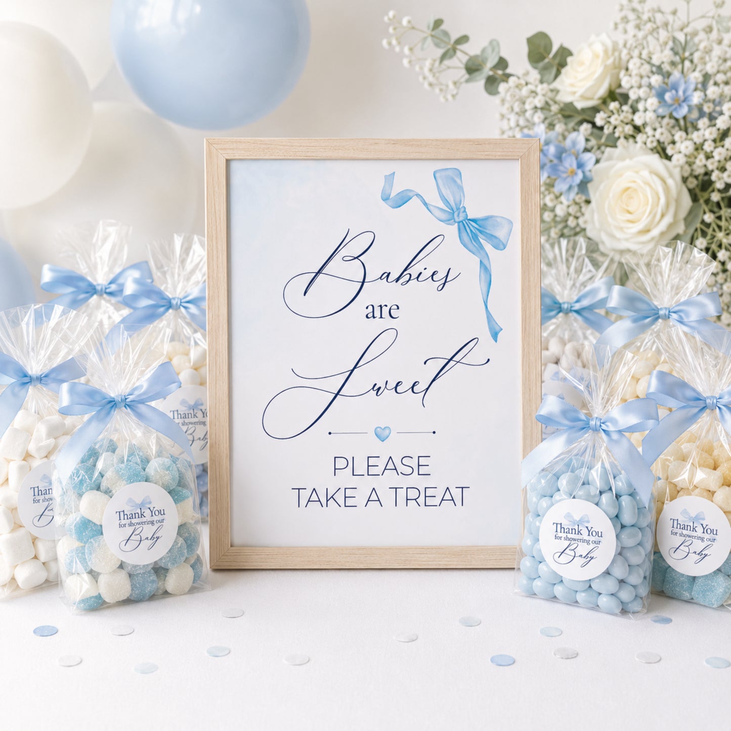 Blue bow baby shower treat table sign with matching favour stickers displayed alongside sweet bags and baby shower party favours