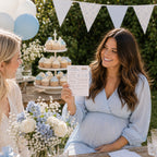 A smiling pregnant woman in a light blue maternity dress holds up a baby shower invitation card at an outdoor teddy baby shower party. Another woman is seated beside her, and the background features balloons, a cupcake stand, and bunting.