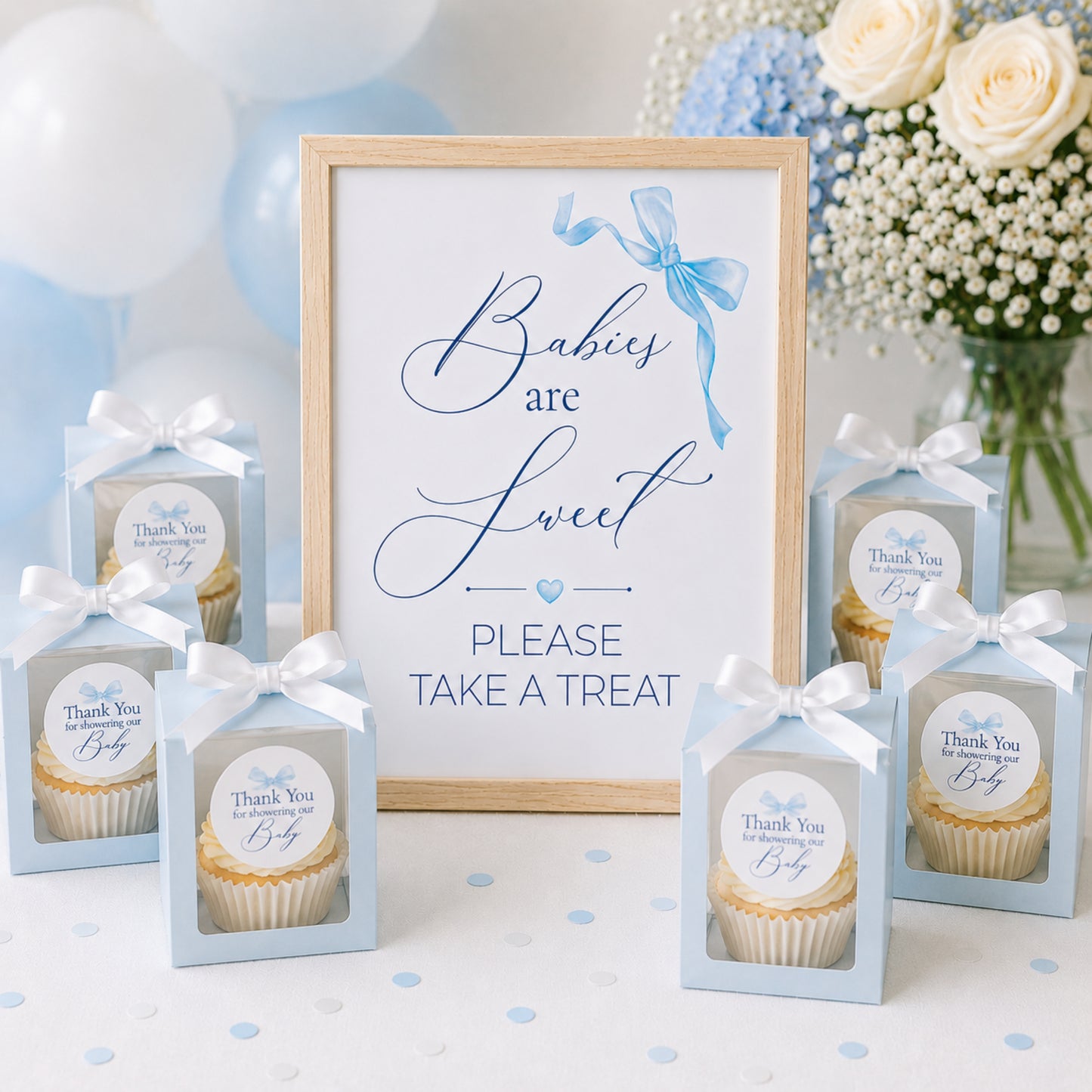 Elegant blue bow baby shower favour sign with matching thank you stickers displayed with cupcake favour boxes and baby boy party decorations