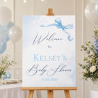 Little Bow Blue personalised baby shower welcome sign with blue bow design displayed on wooden easel for baby boy baby shower venue entrance.