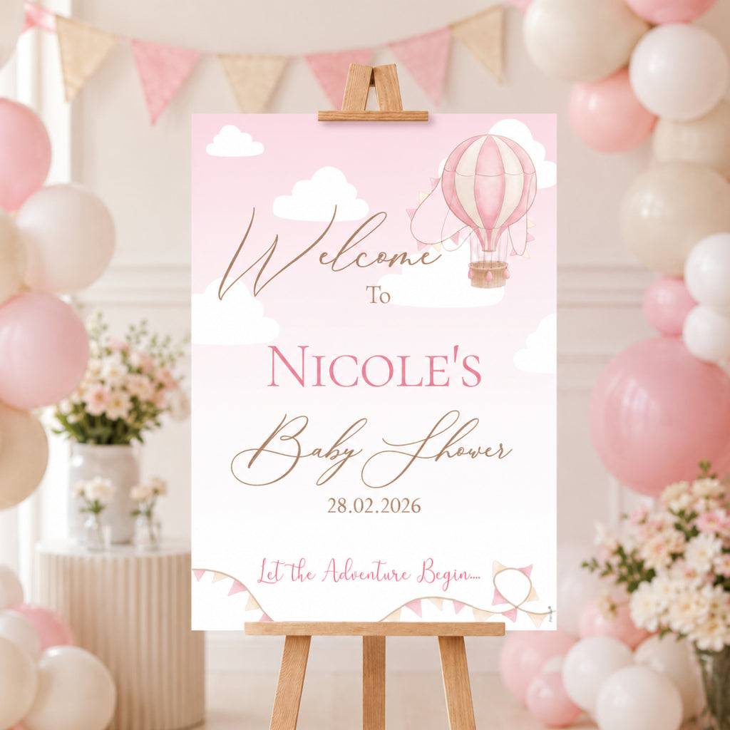 Personalised Up and Away Baby Girl baby shower welcome sign featuring pink hot air balloons, clouds and a custom name displayed on an easel at a pink baby shower venue.