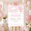 Personalised Up and Away Baby Girl baby shower welcome sign featuring pink hot air balloons, clouds and a custom name displayed on an easel at a pink baby shower venue.