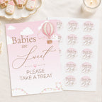 Pink and white baby shower sign and matching sticker sheet with hot air balloon and cursive text reading 'Babies are Sweet PLEASE TAKE A TREAT' on a light fabric background.