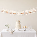 Teddy bear baby shower banner bunting displayed above a neutral baby shower dessert table with teddy cake and cupcakes.
