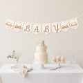 Teddy bear baby shower banner bunting displayed above a neutral baby shower dessert table with teddy bear cake.