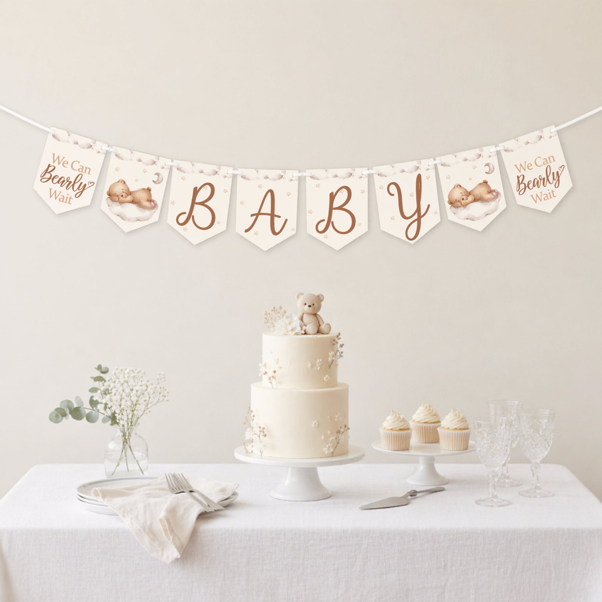 Teddy bear baby shower banner bunting displayed above a neutral baby shower dessert table with teddy bear cake.