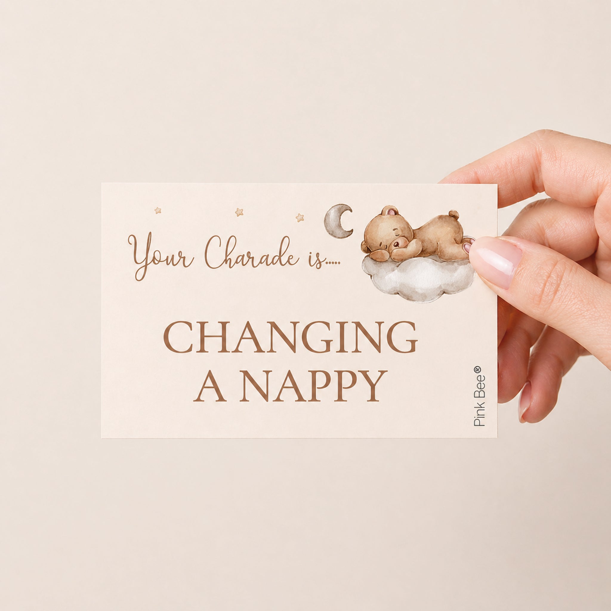 Guest holding a teddy bear baby shower charades clue card showing "Changing a Nappy" during a baby shower party game.