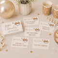 Teddy bear baby shower charades game cards displayed on a neutral party table with balloons, cups and baby shower decorations.
