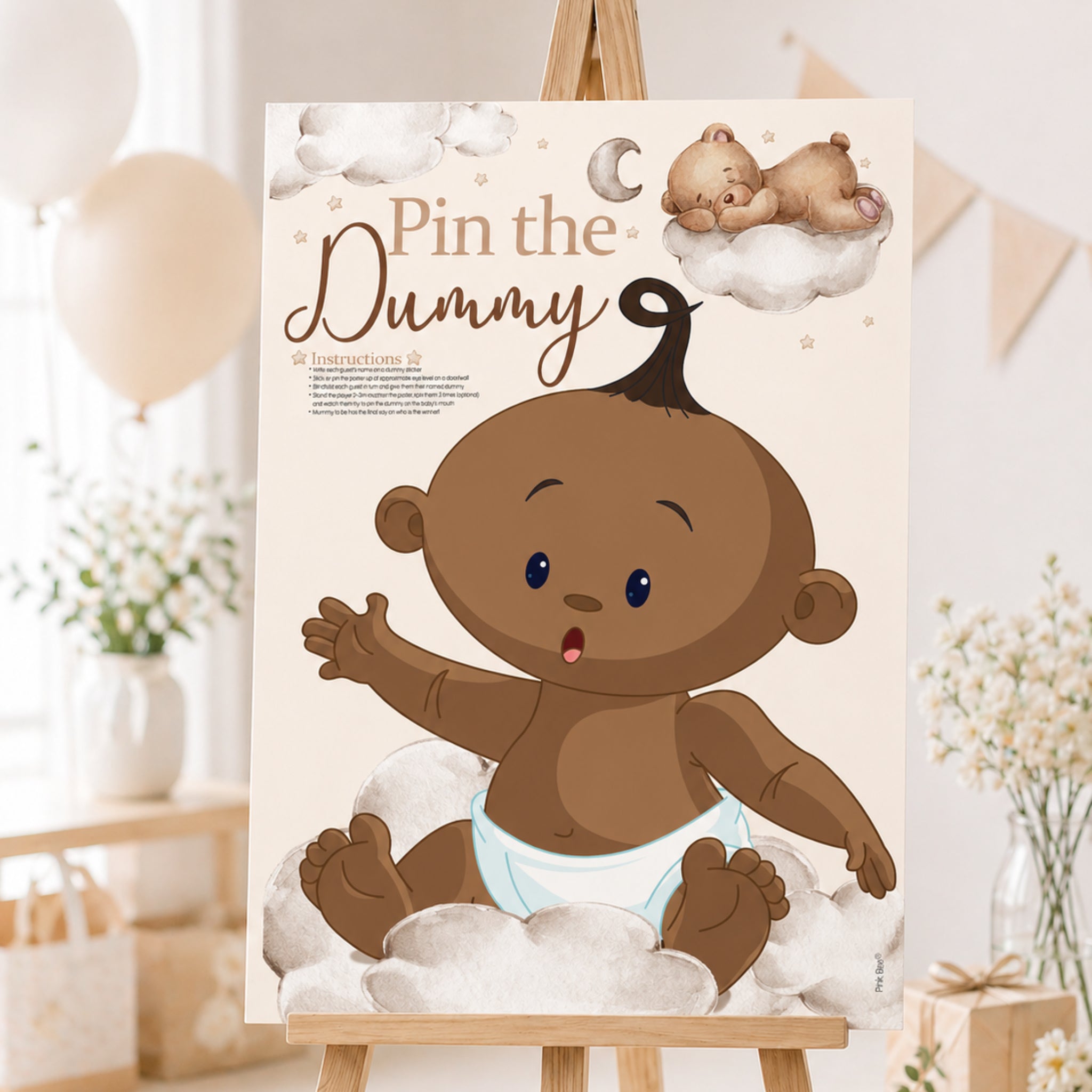A2 Ethnic Teddy Bear Pin the Dummy baby shower game displayed on an easel with teddy bear themed party decorations.