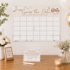 Neutral teddy bear baby shower Guess the Date A2 poster displayed on a wall above a party table with instruction card and baby shower décor.
