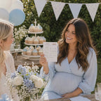 Pregnant mum holding Blue Teddy Bear Baby Prediction Card during an outdoor baby boy teddy bear baby shower, laughing and smiling with guests.